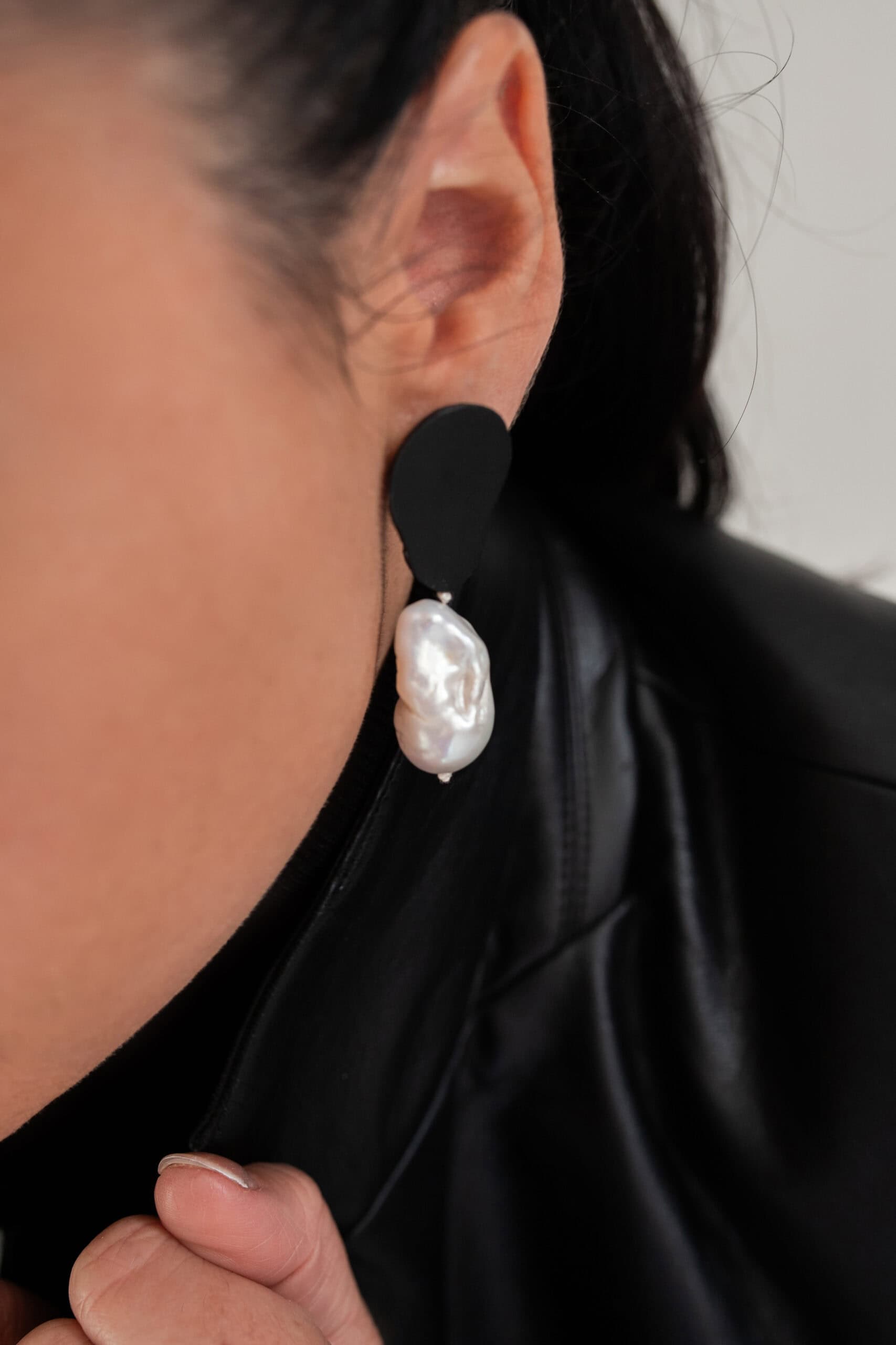 Close-up of leather and baroque pearl earring on ear